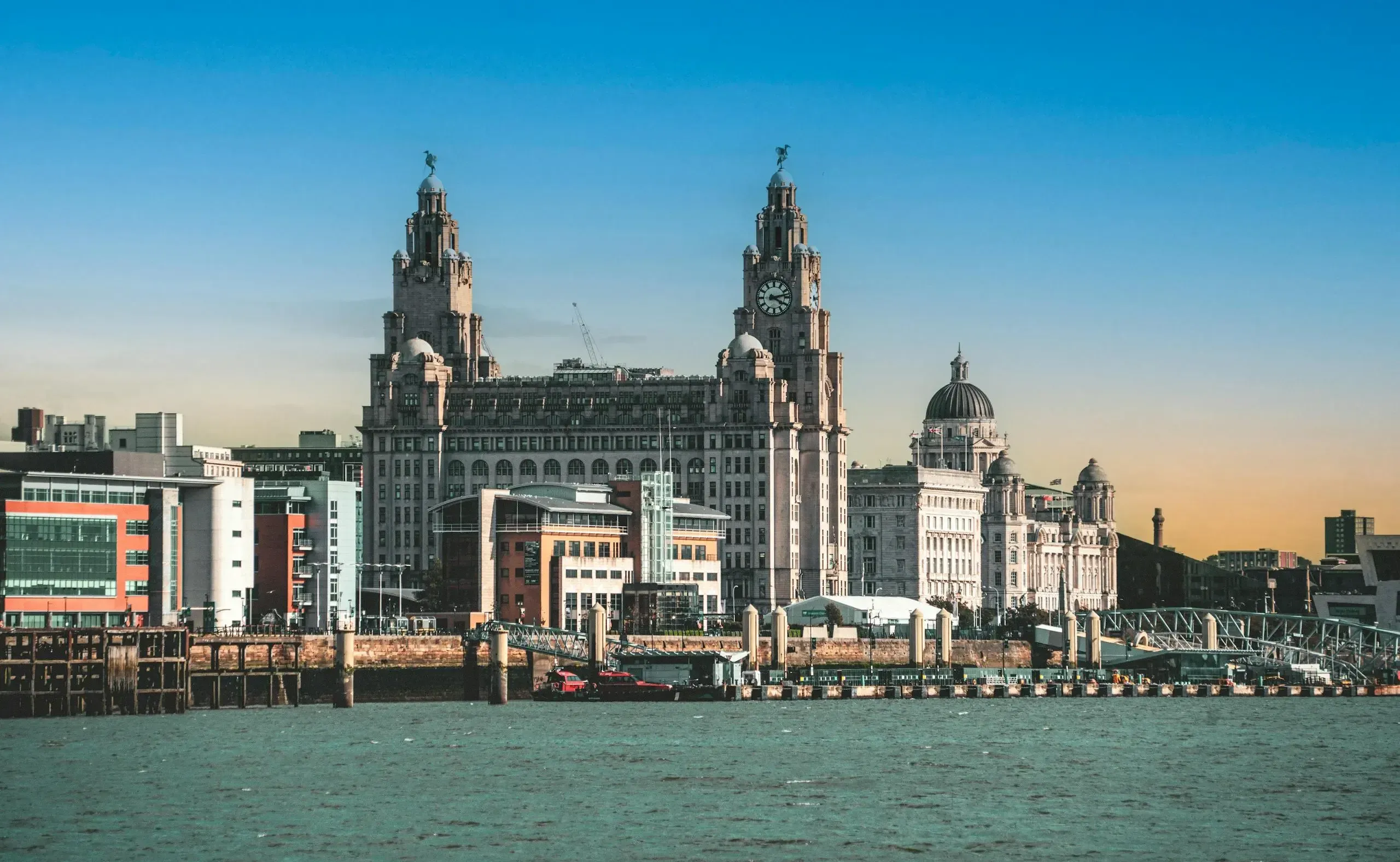 view of the historic liver building and waterfront in liverpool, england at sunset.